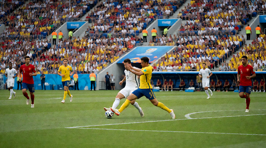 足球比赛现场看台坐满球迷,球场中央正在进行比赛